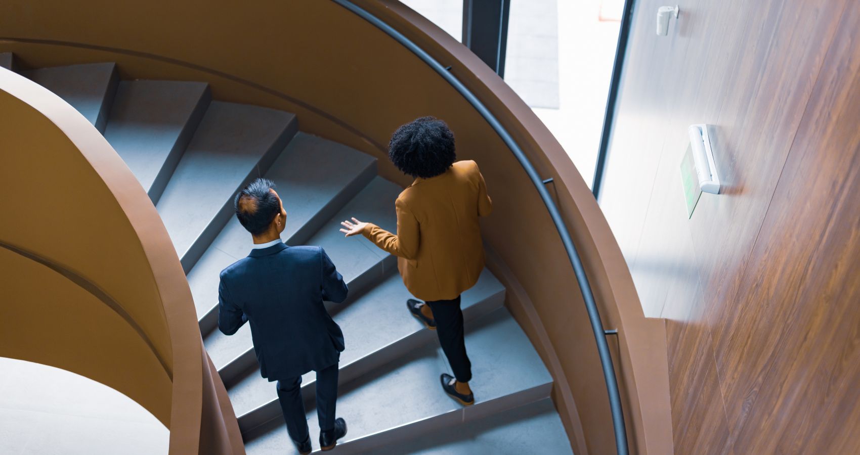 Two business colleagues walking up modern curved staircase